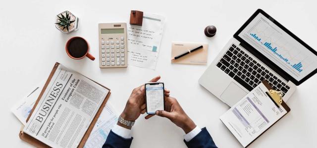 Phone, clipboard, pen and paper on a desk.